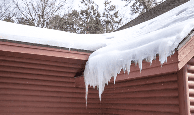 A roof with snow on it and icicles hanging from the side.